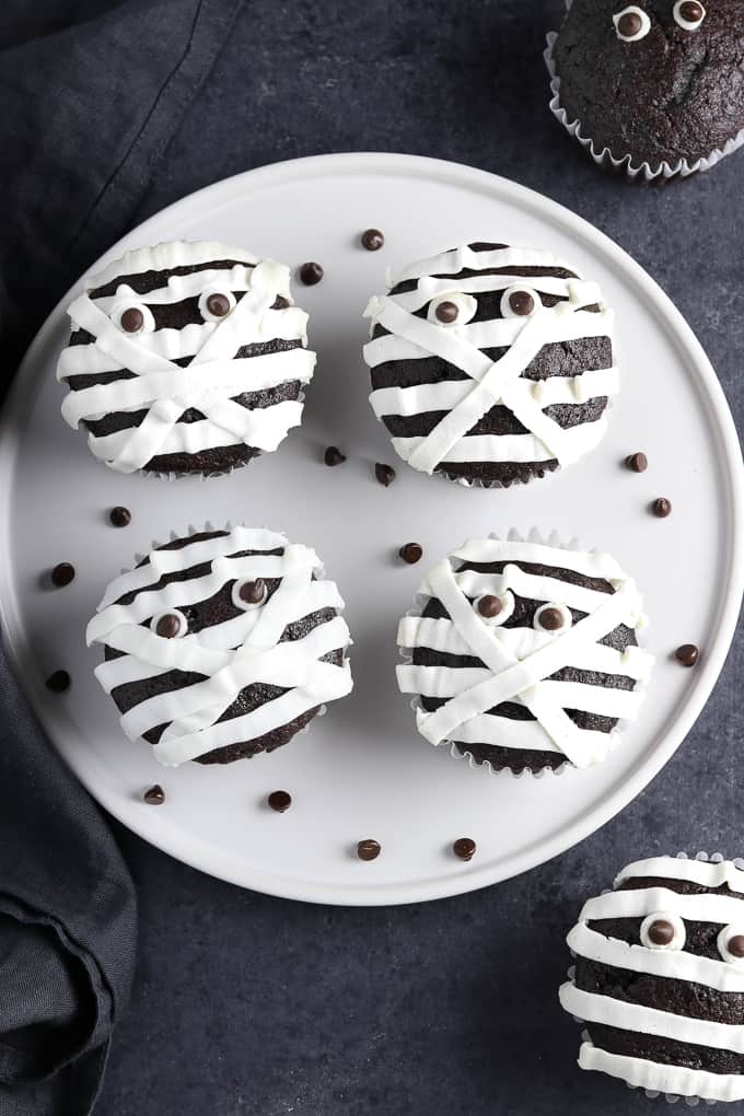 Halloween mummy cupcakes on a white plate with chocolate chips