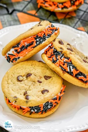 Three Halloween Chocolate Chip Cookies stuffed with frosting and sprinkles on a plate.