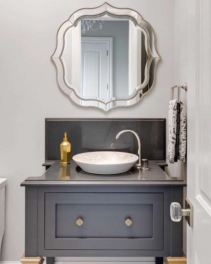 Powder room with ornate farmhouse mirror and vessel sink.